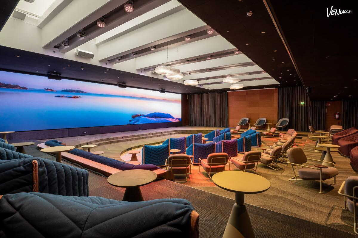 Conference Room Hub 1 at Scandic Helsinki Hub — a tiered auditorium facing a panoramic LED wall showing the Finnish archipelago at dusk